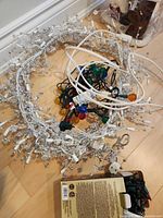 Pile of white icicle lights, multicolour globe bulb lights and cords on floor
