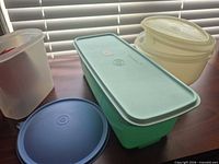 Overview showing green rectangular container with aqua lid, frosted rectangular container, blue round lid, pale yellow bowl with lid