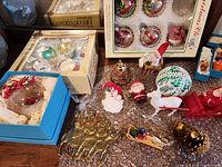 Group shot of entire lot showing boxed ornaments, brass reindeer piece, figurines, sleighs and small decorations