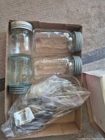 Box containing three Crown sealer jars and bag of mixed flatware