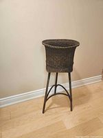 Full view of wicker planter stand against wall