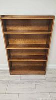 front view of the medium-brown wood bookshelf showing four shelves
