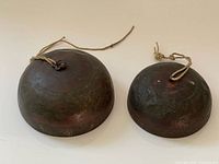 Both copper bells showing size difference and cords attached