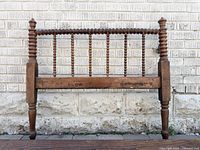 Front view of wood Jenny Lind headboard showing turned spindles and wear
