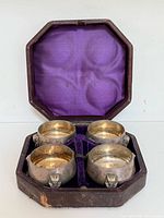 Set of four silver-plated salt cellars inside purple-lined octagonal leather case