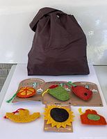 Overview showing brown tote and seven assorted novelty loofah scrubbers, four on original Loofah-Art cards, three loose