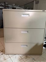 Front view of beige 3-drawer lateral file with lock and recessed pulls