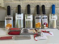 Front view of seven packaged Microplane graters with black and blue handles plus two red-handled graters and product cards