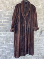 Full view of mahogany mink fur coat hanging, showing collar, cuffs, length, button
