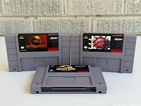 Front view of three SNES cartridges: Mortal Kombat, NBA Jam, Jurassic Park