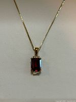 Front view of garnet and diamond pendant on gold chain