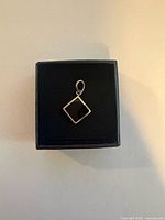 Front view of square black onyx pendant in sterling silver bezel, in box