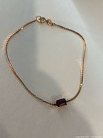 Full view of bracelet laid flat showing chain, garnet setting and clasp