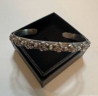 Sterling silver floral cuff bangle on display box, showing inner stamping and rose detailing