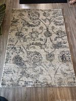 Full view of the 66 x 46 in beige and grey patterned area rug on floor