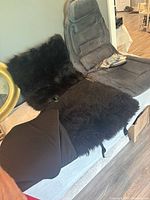 Gray heated/vibrating seat cover, black shearling seat cover displayed on bench