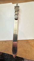 Full view of silver letter opener showing handle with coins and blade