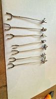 Six silver cocktail picks lined up to show shape and finials