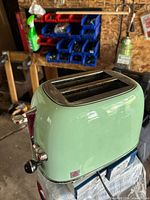 Front angled view of pastel mint green 2-slice toaster on bench