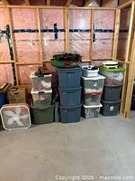 Overall view of stacked storage totes, fan, wreath and tree stand