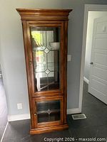 Full view of wooden display cabinet showing doors and glass panels