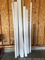 Stack of assorted white primed trim boards and one unfinished board leaning against wall