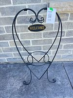 Full view of heart-shaped black metal plant stand with Welcome sign
