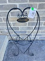 Full view of black metal heart-shaped plant stand with Welcome plaque