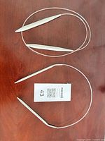 Two circular knitting needles laid flat on wood surface