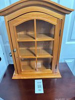 Front view of arched-top display cabinet showing glass door and shelves