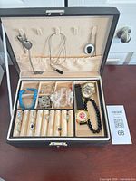 Open jewelry box showing necklaces on lid and assorted jewelry pieces in compartments
