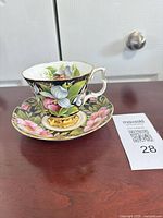 Teacup on saucer showing exterior floral design and gold trimmed handle