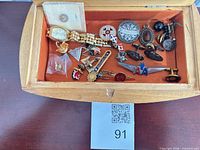Top view of open wooden jewelry box showing contents