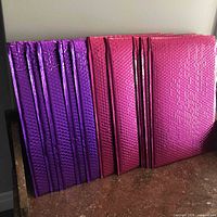 Stacked view showing ten metallic bubble mailers in pink and purple