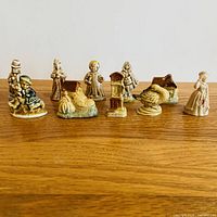 Front view of all 10 Wade England nursery rhyme figurines on wooden surface