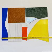 assorted stained glass offcuts with measuring tape for scale