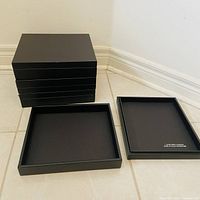 Stack of four black faux leather boxes with one open showing interior