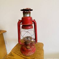 Front view of red Beacon oil lantern on table