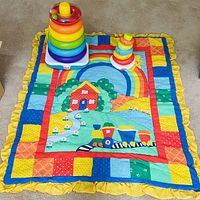Quilt laid out flat with both stacking toys displayed