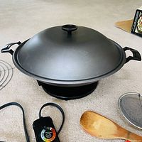 Electric wok assembled with lid, racks, cord, spatula, mesh strainer visible