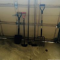 All five long-handled tools leaning against wall