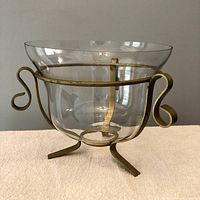 Full view of glass bowl mounted in brass-tone metal stand on neutral background