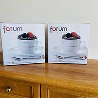 Two sealed Forum Cafe Sweet Cakes sets on cabinet