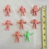 Front view of all eight mini figures with ruler for scale