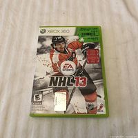 Front view of Xbox 360 NHL 13 game case showing cover art and platform branding
