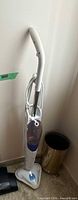 Full view of white and blue H2O steam mop standing upright against wall
