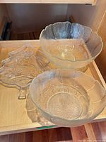 Two clear pressed glass bowls and one leaf-shaped platter inside drawer