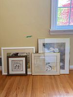 Group of four framed artworks leaning against wall