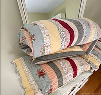 Folded quilt and pillow shams stacked on dresser