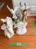 Group shot of seven visible porcelain figurines on wooden floor
